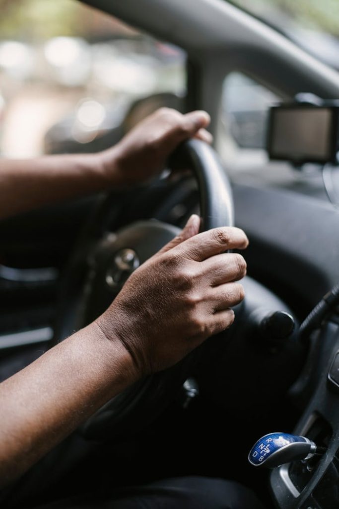 Person holding steering wheel of car Person holding steering wheel of car